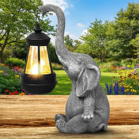 Decorative elephant statue with a solar lantern on a wooden surface, garden background